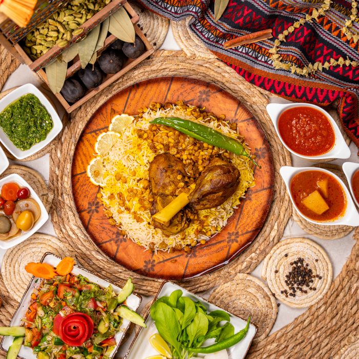 Lamb kabsa on spiced rice surrounded by sauces and sides