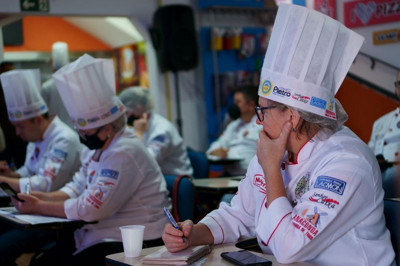 Chefs in white uniforms and hats taking notes during a culinary class